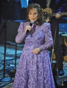 Loretta Lynn onstage in sparkly purple dress