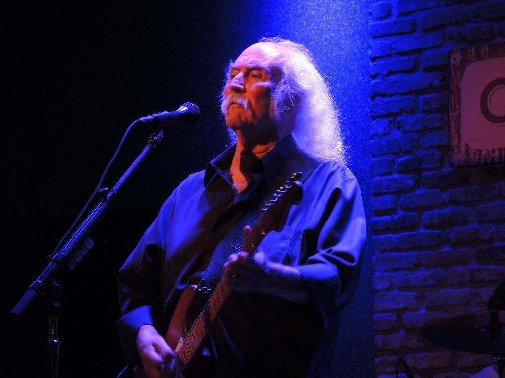 David Crosby onstage with guitar, bathed in blue spotlight