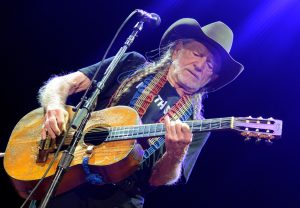 Willie Nelson on stage with beat up acoustic guitar (Trigger)