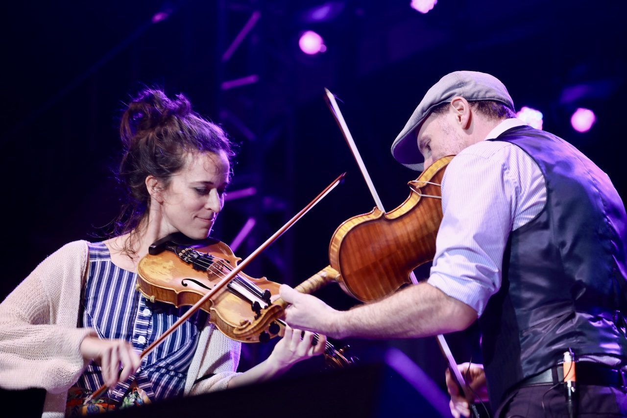 Two fiddle players jam onstage