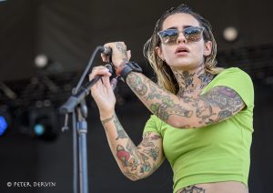 Morgan Wade onstage in lime green shirt and sunglasses, arms heavily tattooed
