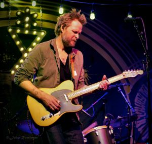 MC Taylor of Hiss Golden Messenger plays a yellow electric guitar onstage