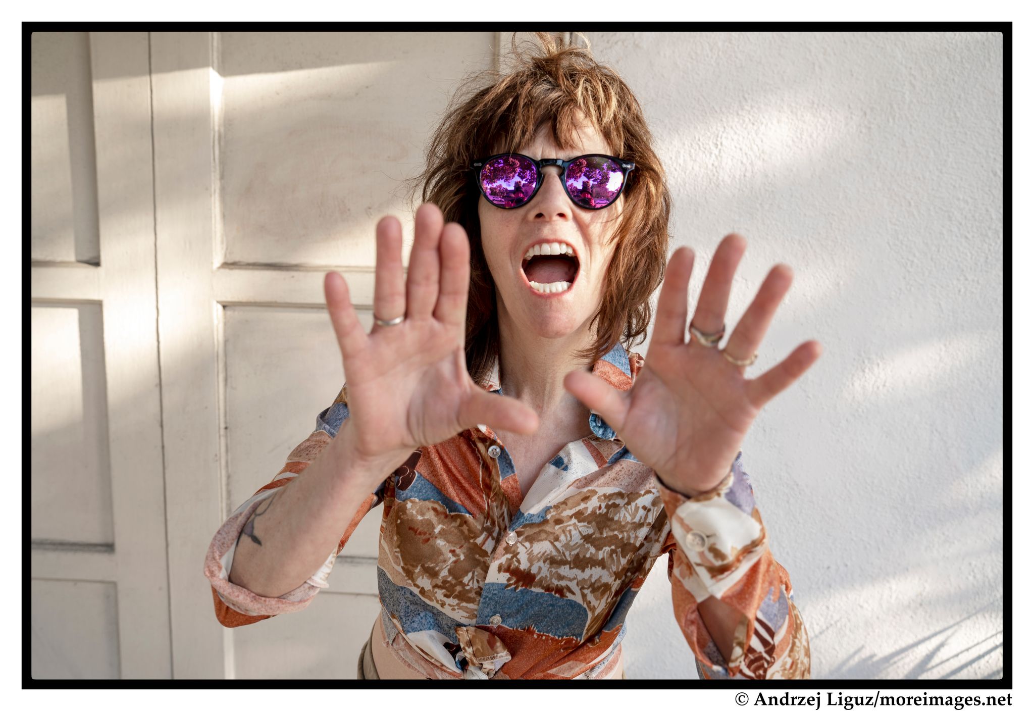 Amelia White portrait in colorful shirt with hands by face as if shouting