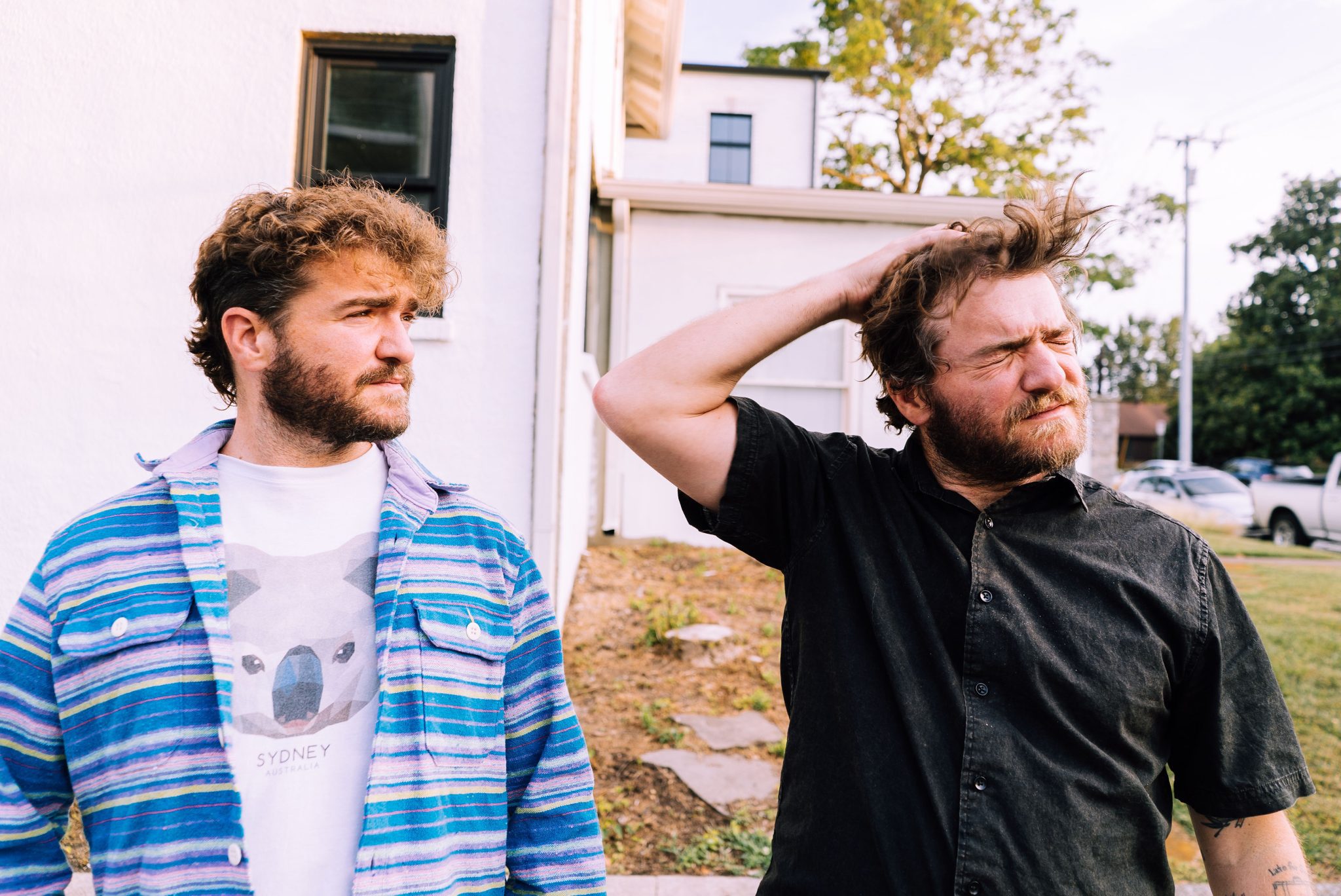 Twin brothers Adam Moss and David Moss of the Brother Brothers standing outside looking right