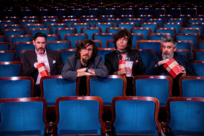 The four members of the Mountain Goats sit in a movie theater