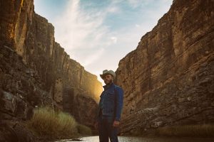 Charley Crockett in a jean jacket at the bottom of a canyon