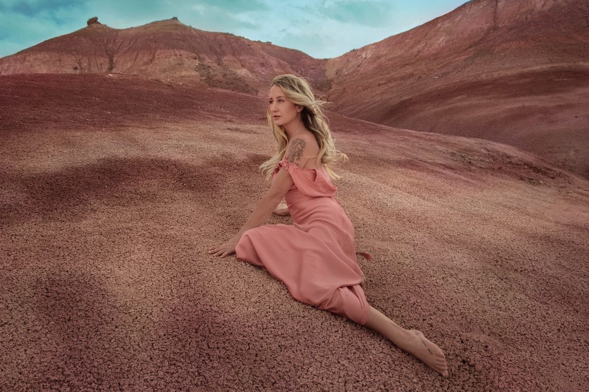 Margo Price in a pink dress on pink desert sand