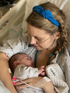 A mother holds her baby in a hospital bed