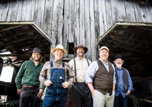The five members of Appalachian Road Show in front of a barn