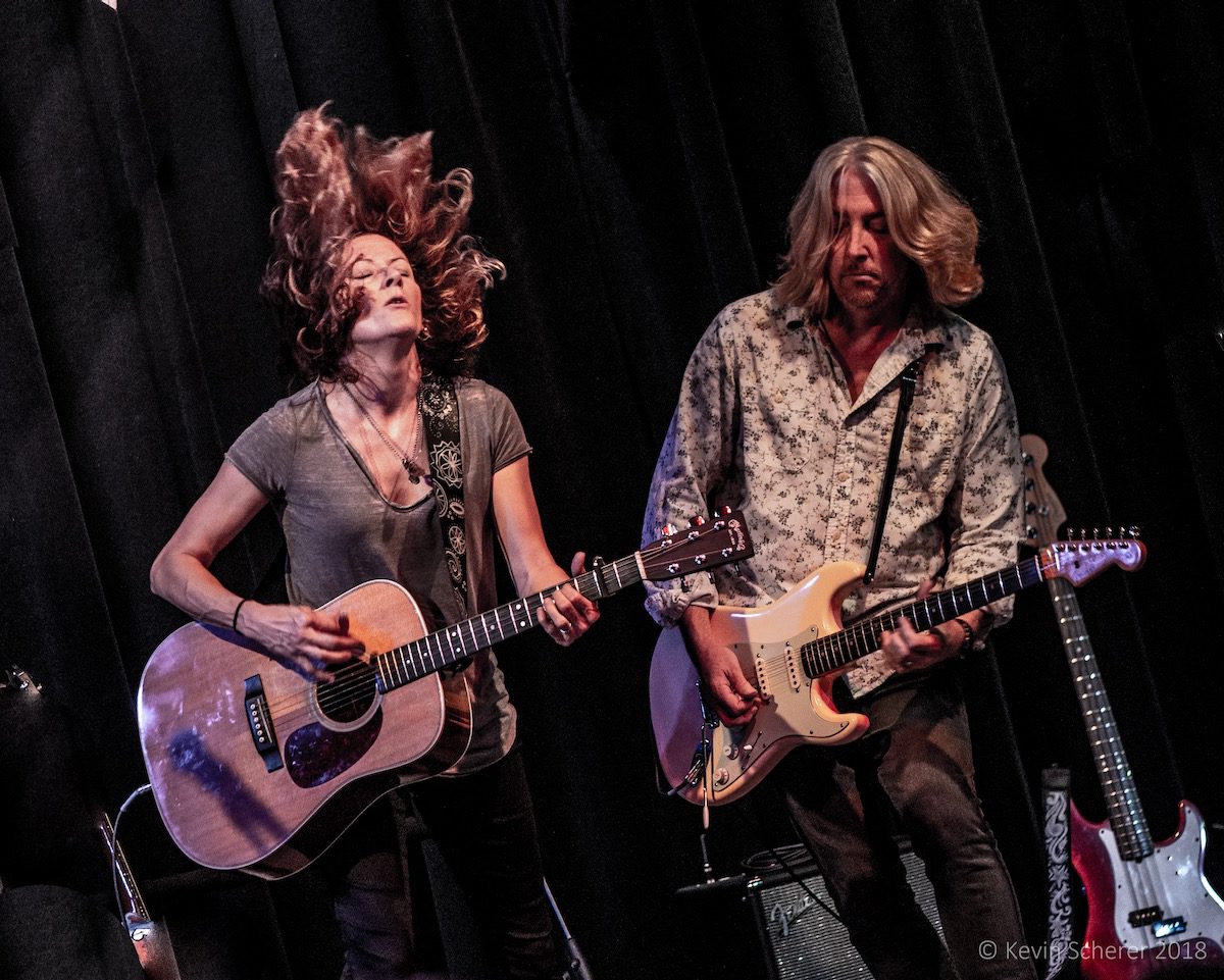 Michelle Malone and the Hot Toddies onstage, with Malone flipping her hair as she plays guitar