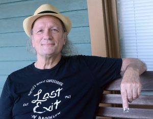 Grant Dermody sits on a porch with harmonica