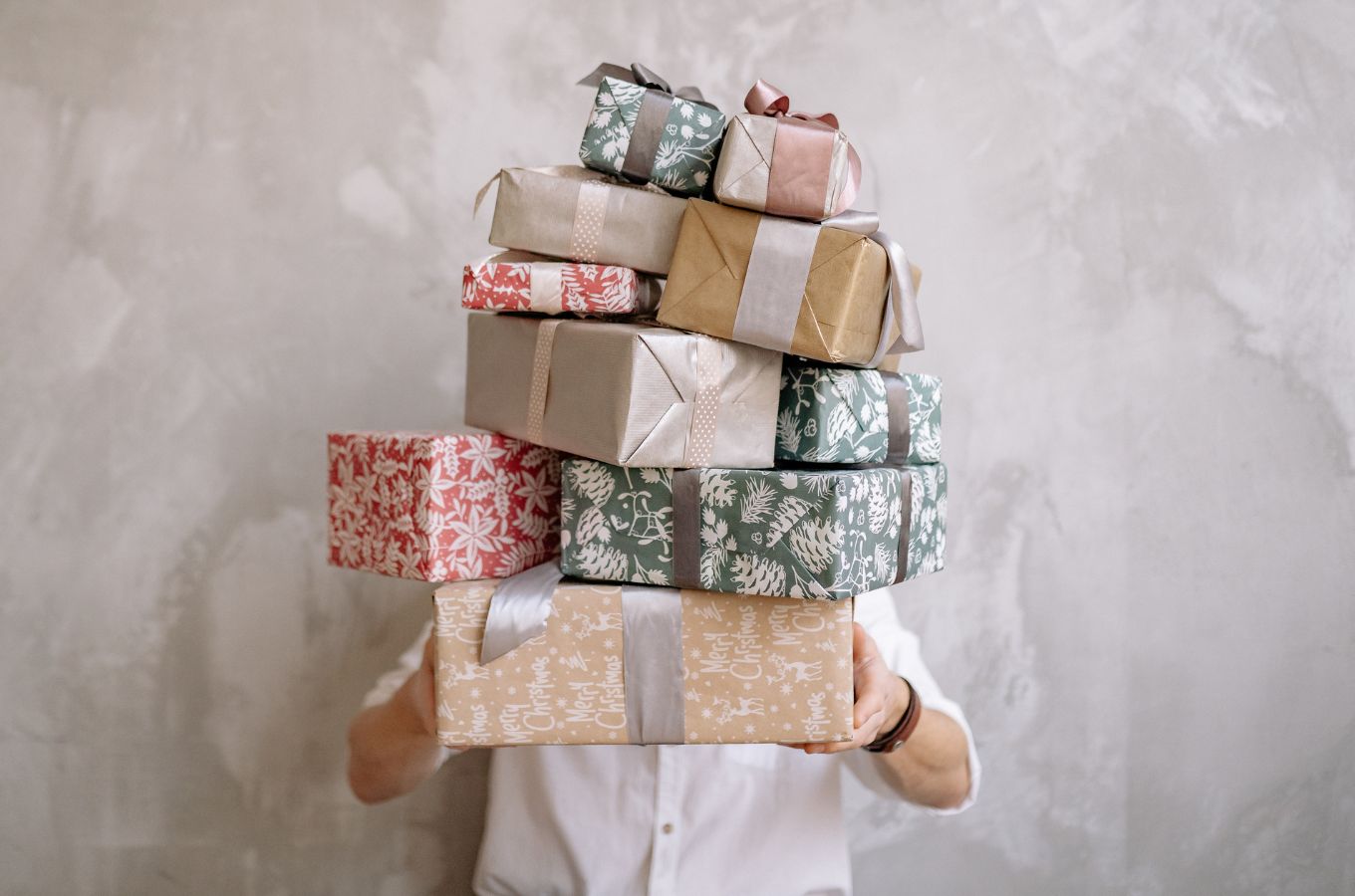 A person carrying a high stack of wrapped gifts