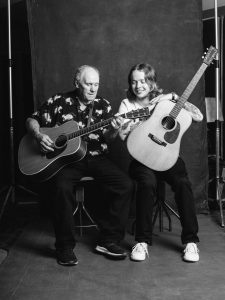 Billy Strings sits with his stepdad, Terry Barber, in front of a photo backdrop