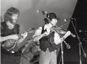 A black and white photo of Sam Bush and John Hartford playing music onstage