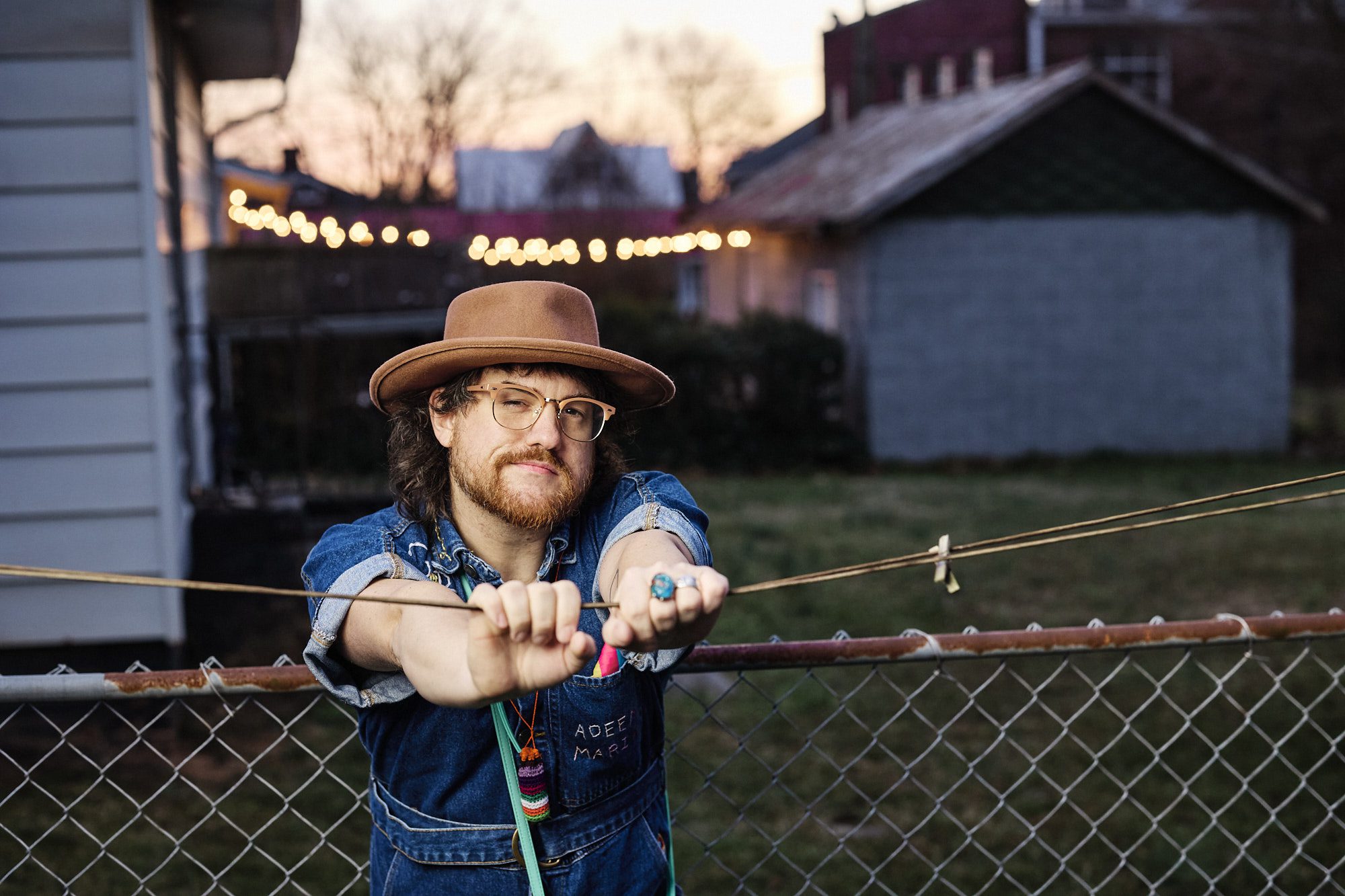 Adeem the Artist leaning on a chain link fence