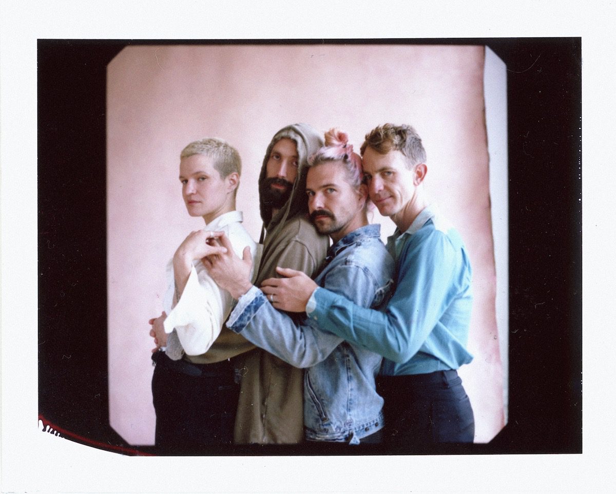 The four members of Big Thief in profile against a pink wall