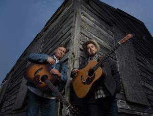 Gibson Brothers standing against an aged barn