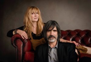 Teresa Williams reclines on a sofa while Larry Campbell sits on the floor in front of her.