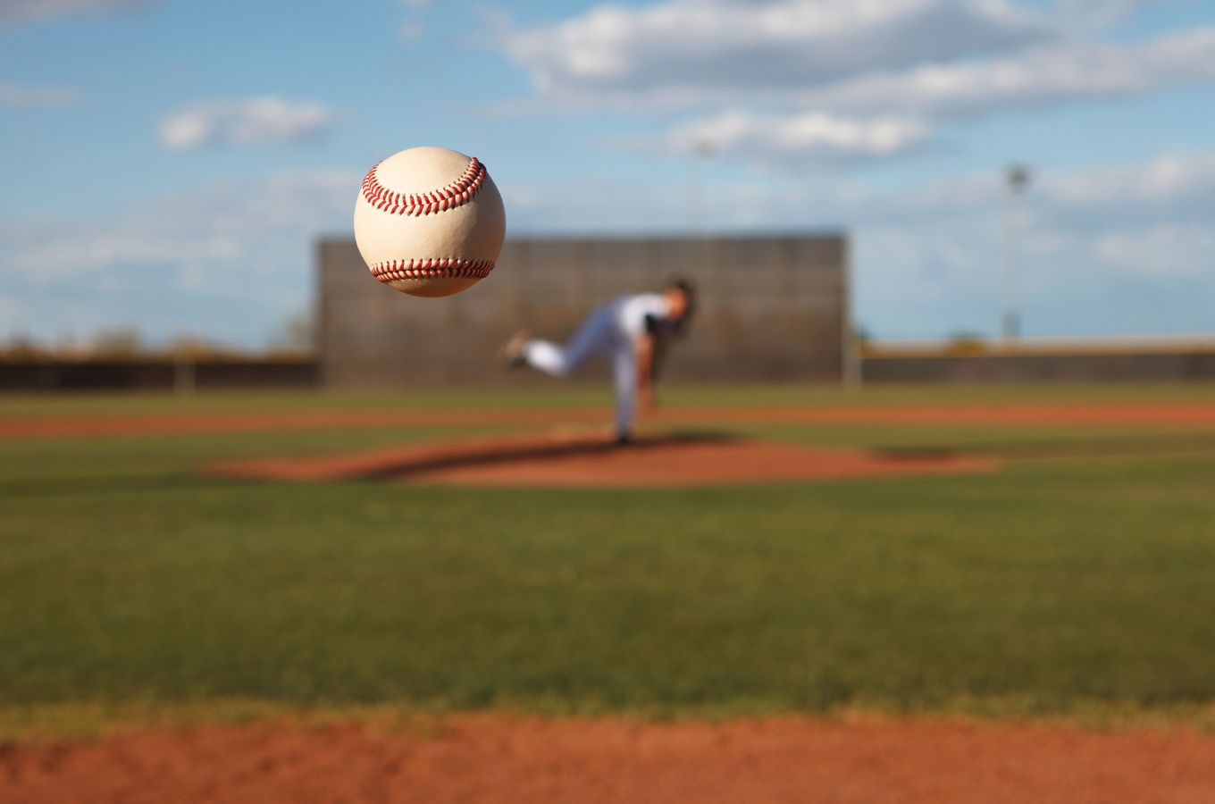 a baseball flies toward the camera with a baseball field blurred in the background