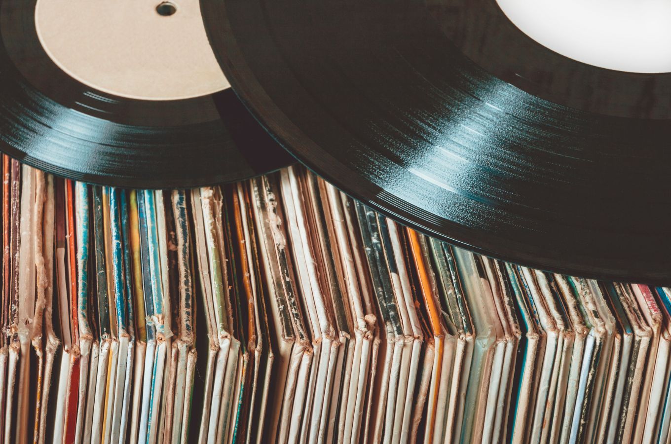 a row of worn record sleeves with two black discs placed on top
