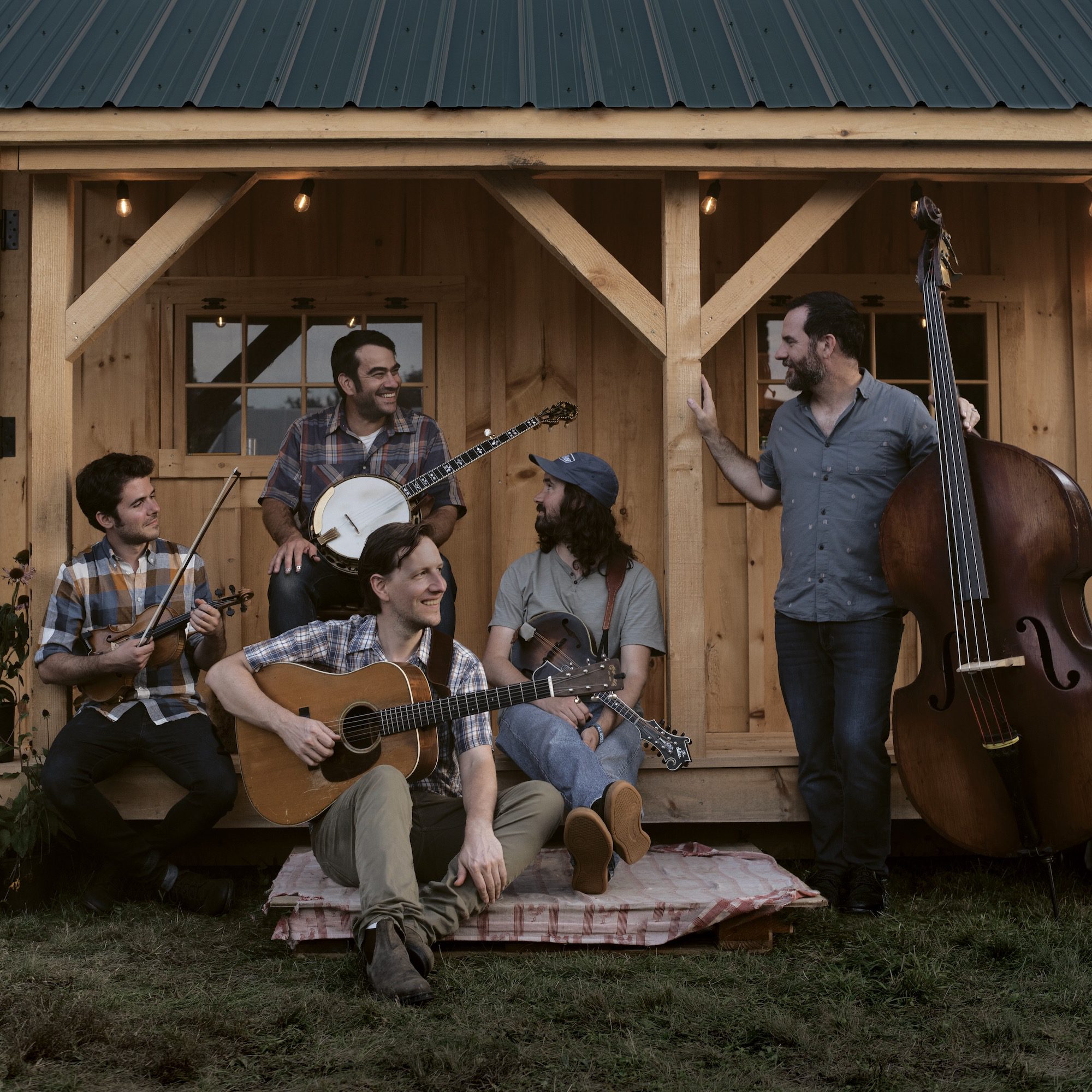 The five members of Mighty Poplar sit on a front porch with their instruments