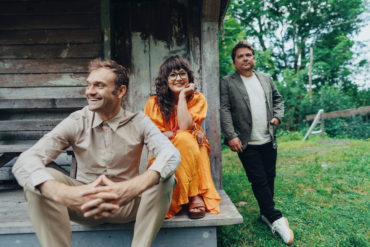 Nickel creek on the front stoop of a rural wooden structure