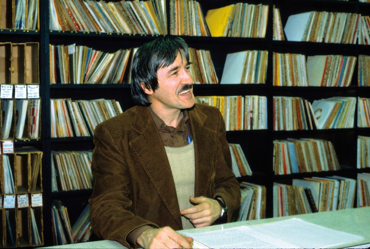 Skippy White sits at a table in front of shelves of records