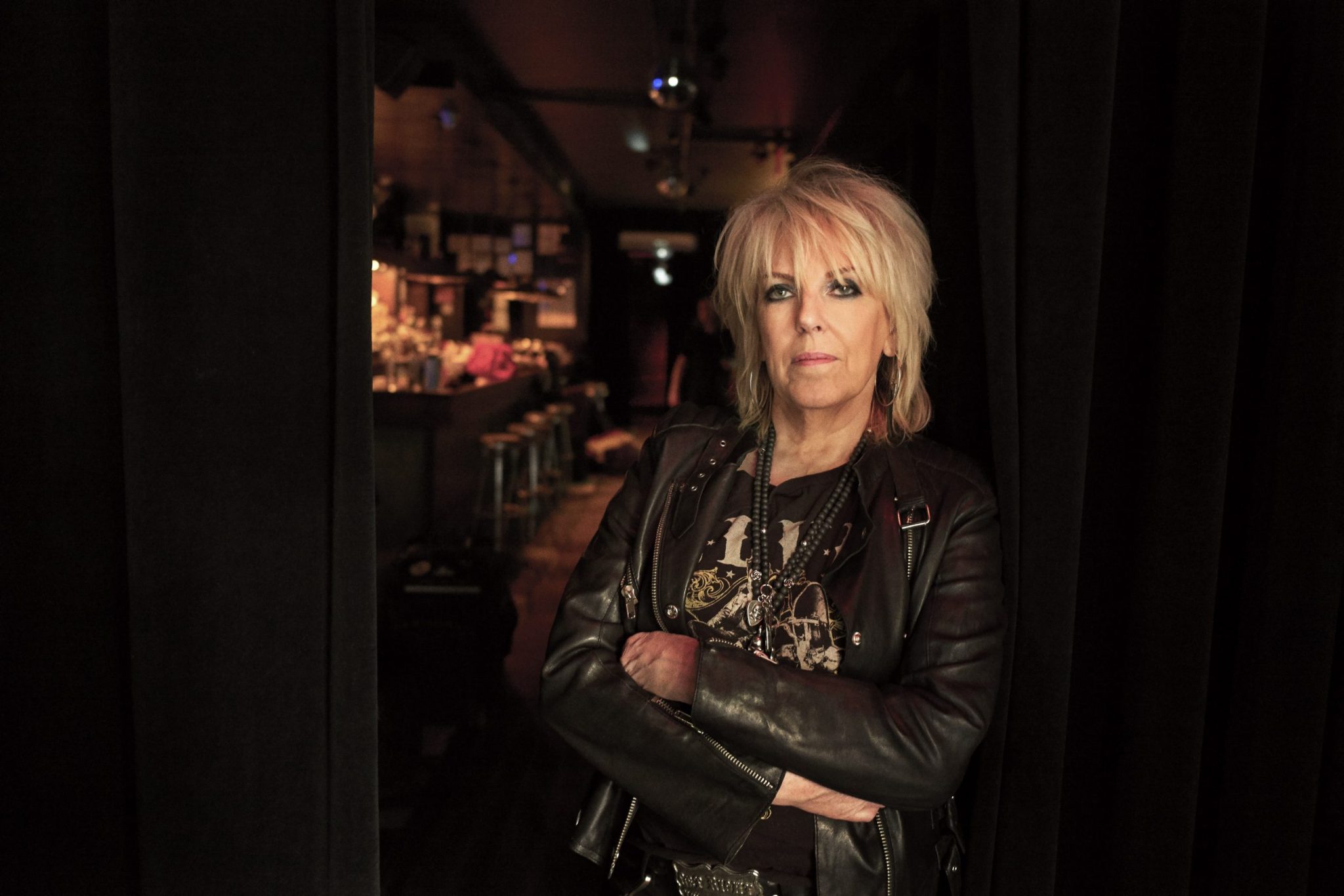 Lucinda Williams stands in a door way of a bar