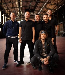 The six members of Dropkick Murphys wearing all black in a warehouse