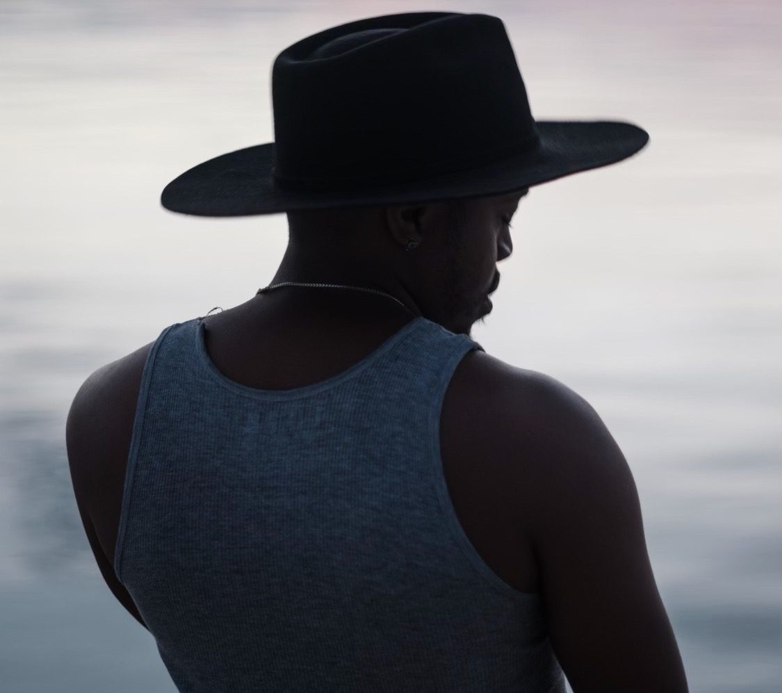 Durand Jones with his back to the camera, looking toward a lake at dusk