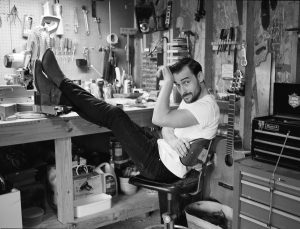 Robert Ellis in a workshop with his feet up on a wooden bench