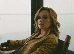 Brandy Clark in a brown shirt seated next to a window