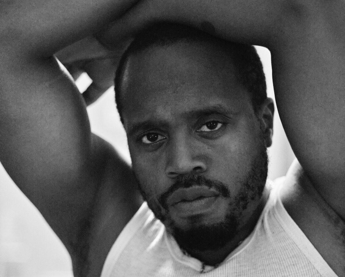 Black and white portrait of Durand Jones with arms crossed over his head