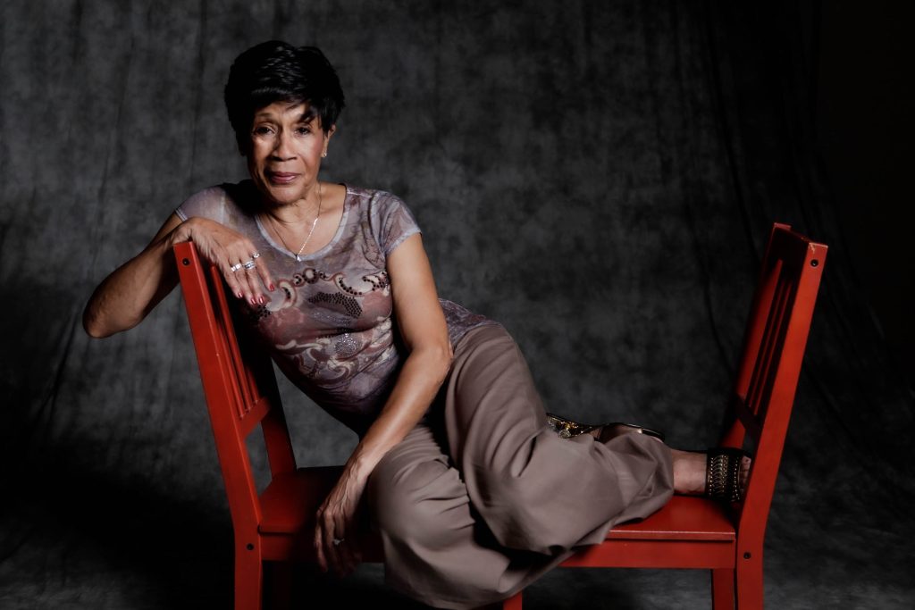 Bettye LaVette lounges across two red chairs
