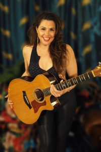 Sara Petite holding an acoustic guitar