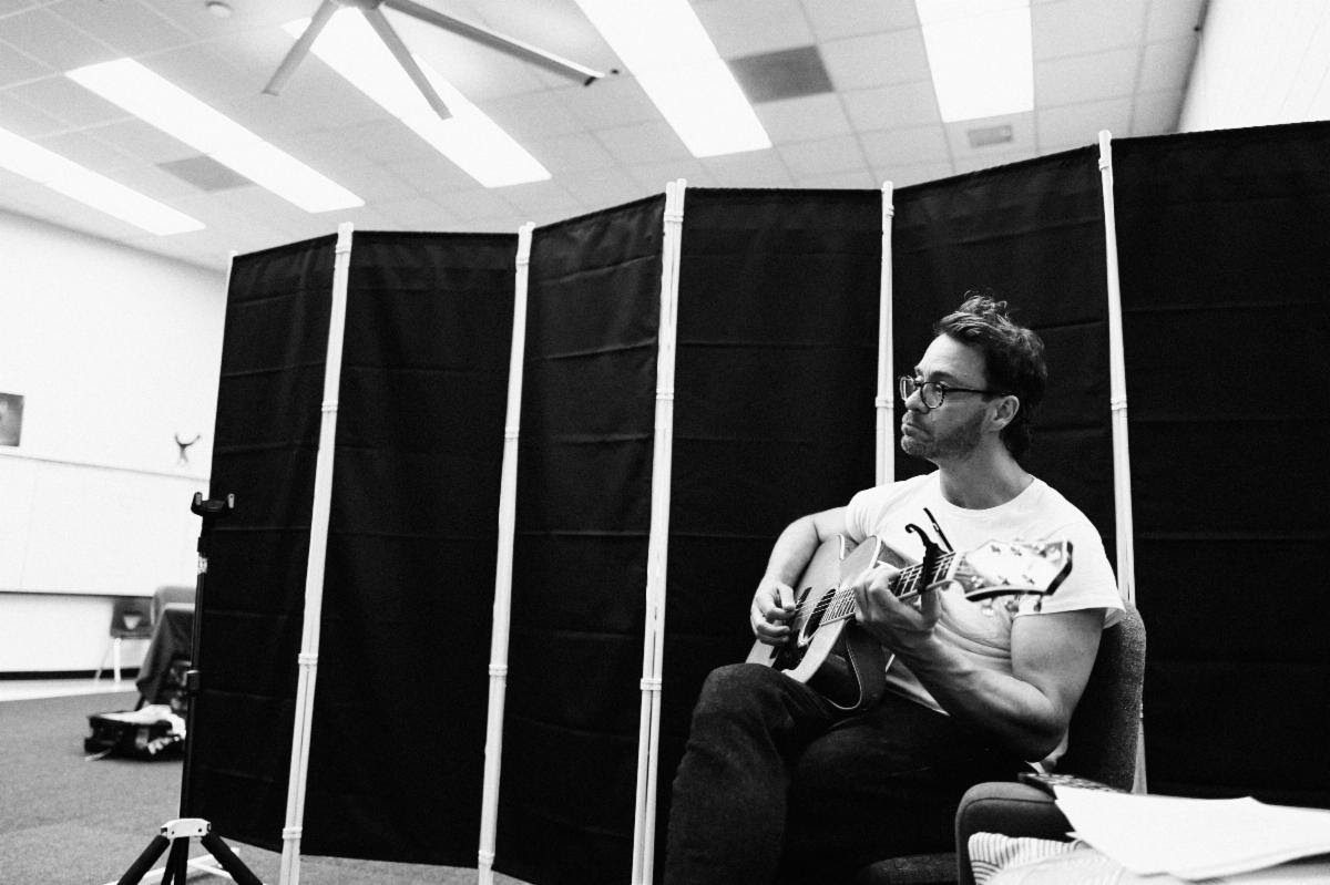 Amos Lee sits with acoustic guitar