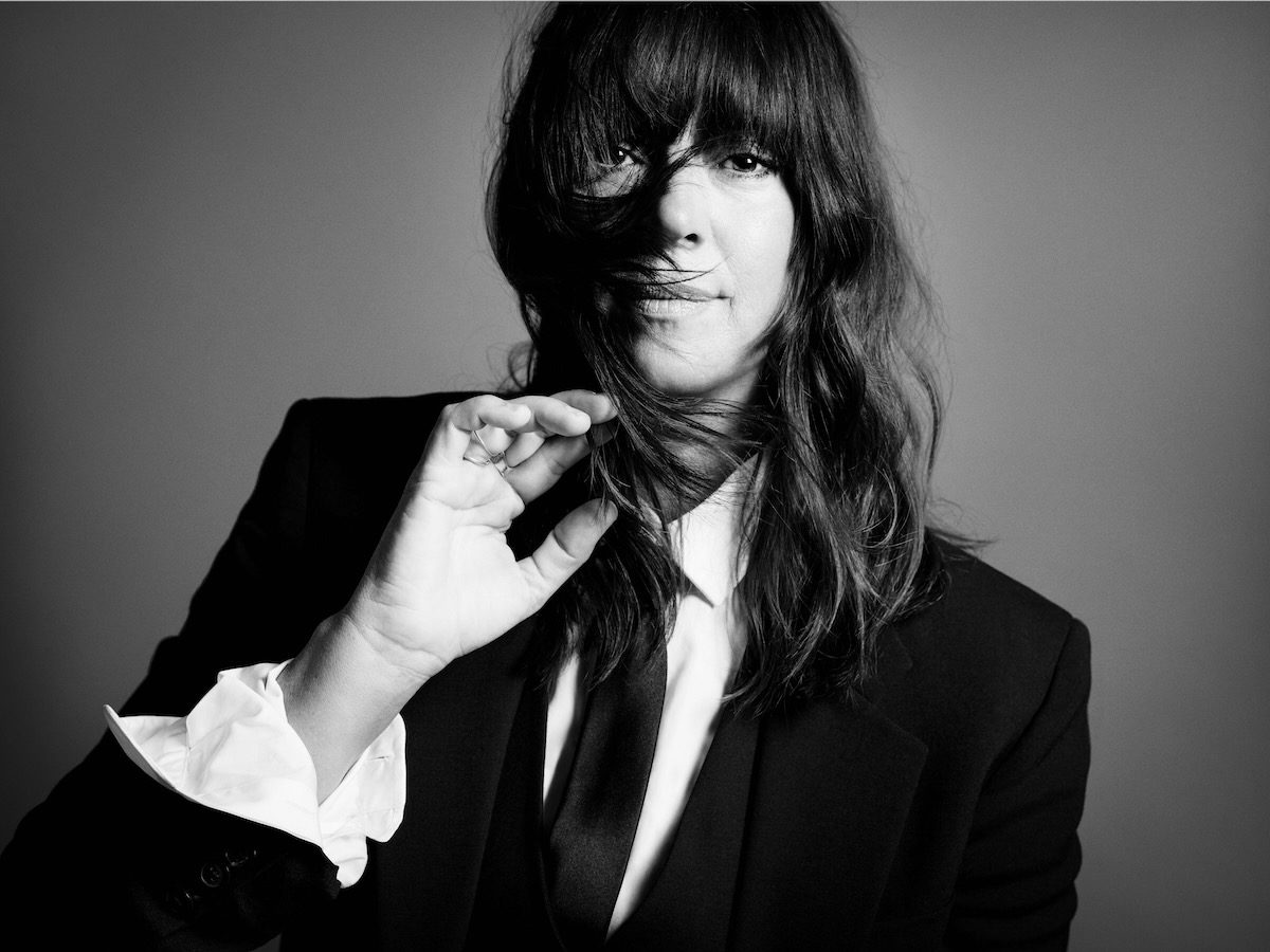 Black and white portrait of Cat Power in white shirt, black blazer, and black tie