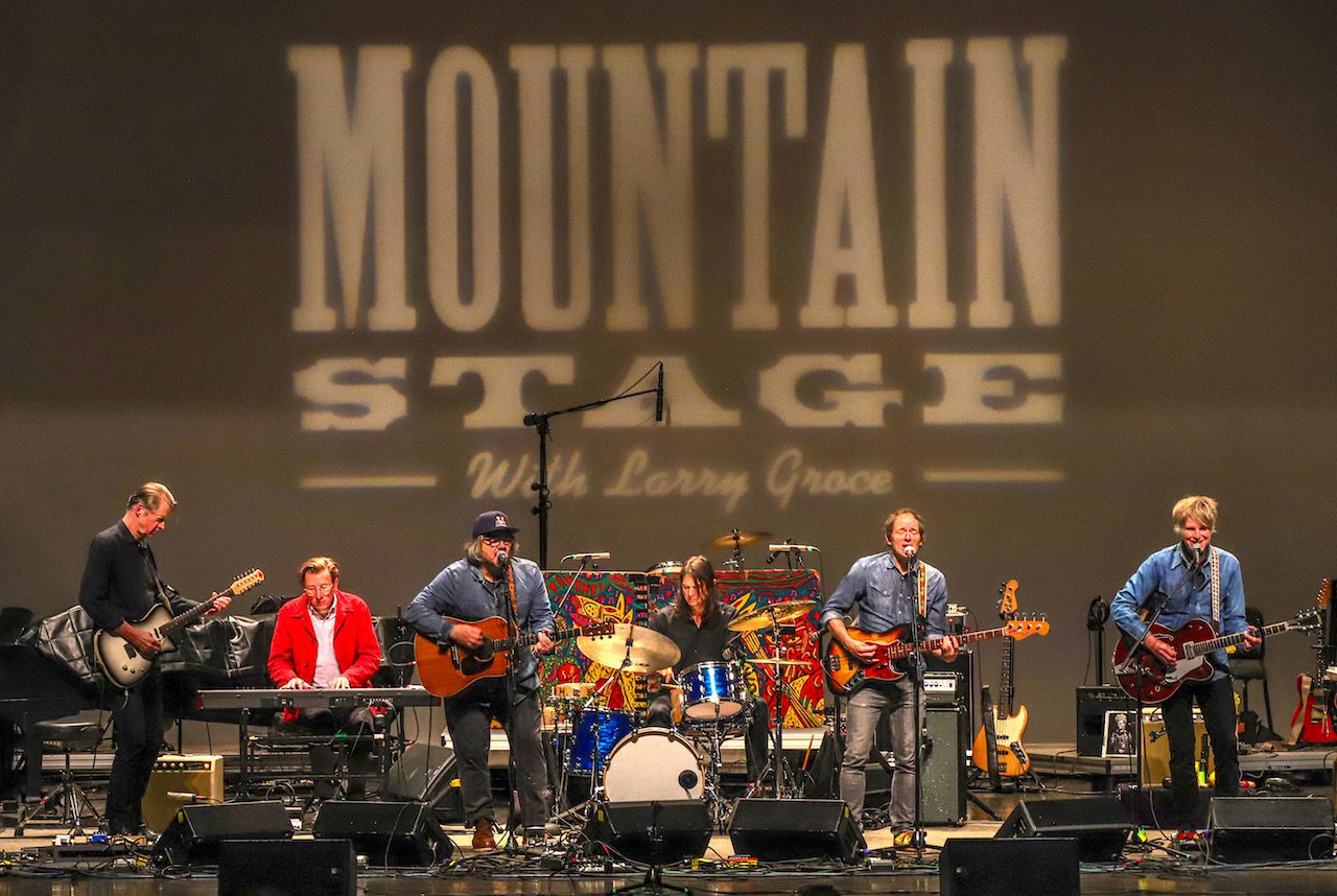 Wilco performs on a stage with a Mountain Stage backdrop
