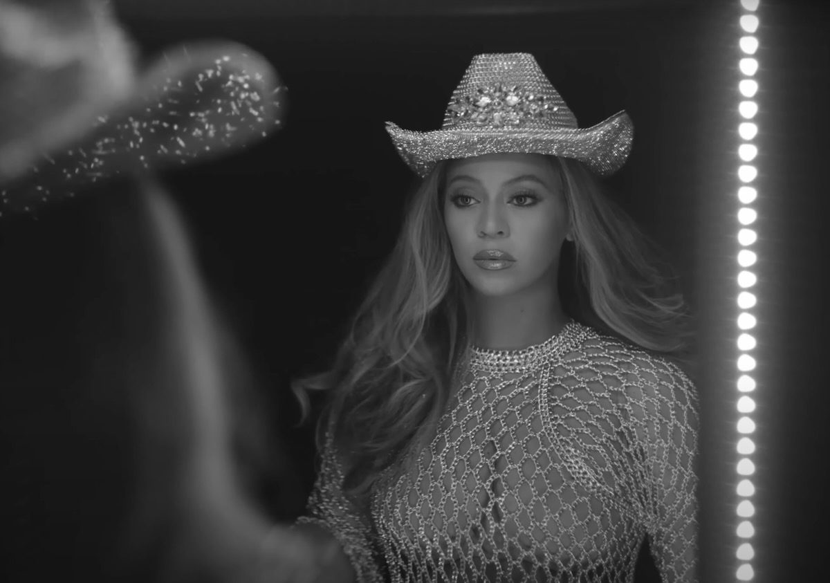 Beyonce looking in a mirror, wearing a spangled cowboy hat