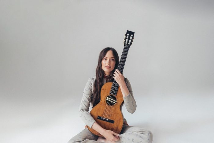Kacey Musgraves sits on the floor with a classical guitar