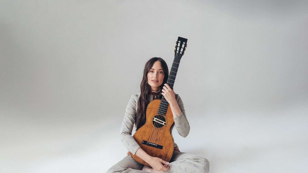 Kacey Musgraves sits on the floor with a classical guitar