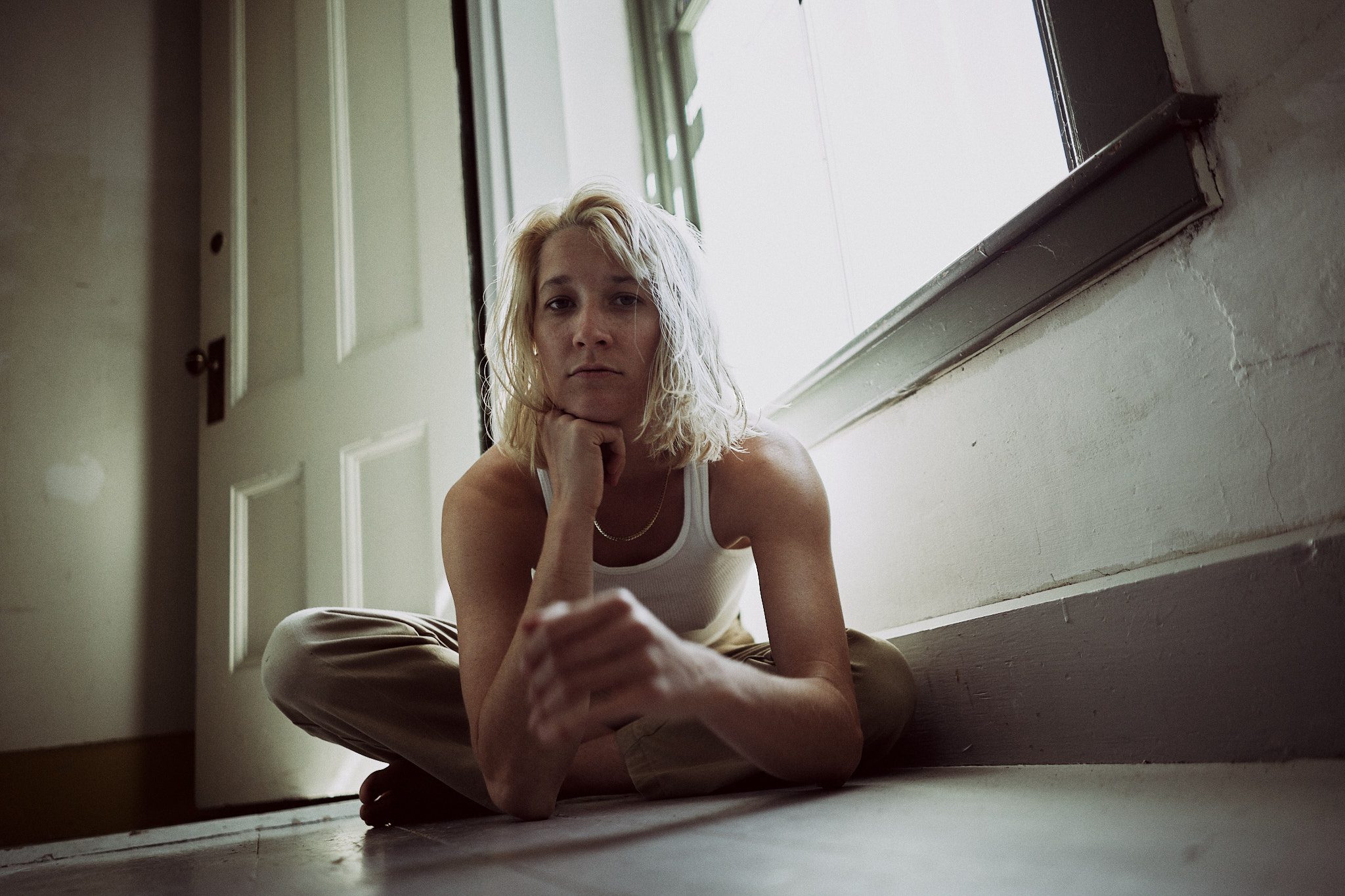 A portrait of Louisa Stancioff leaning forward while seated on an interior floor