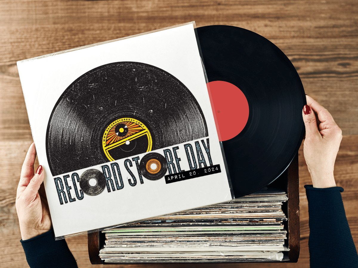 A pair of hands removes a record from its sleeve over a bin of more records