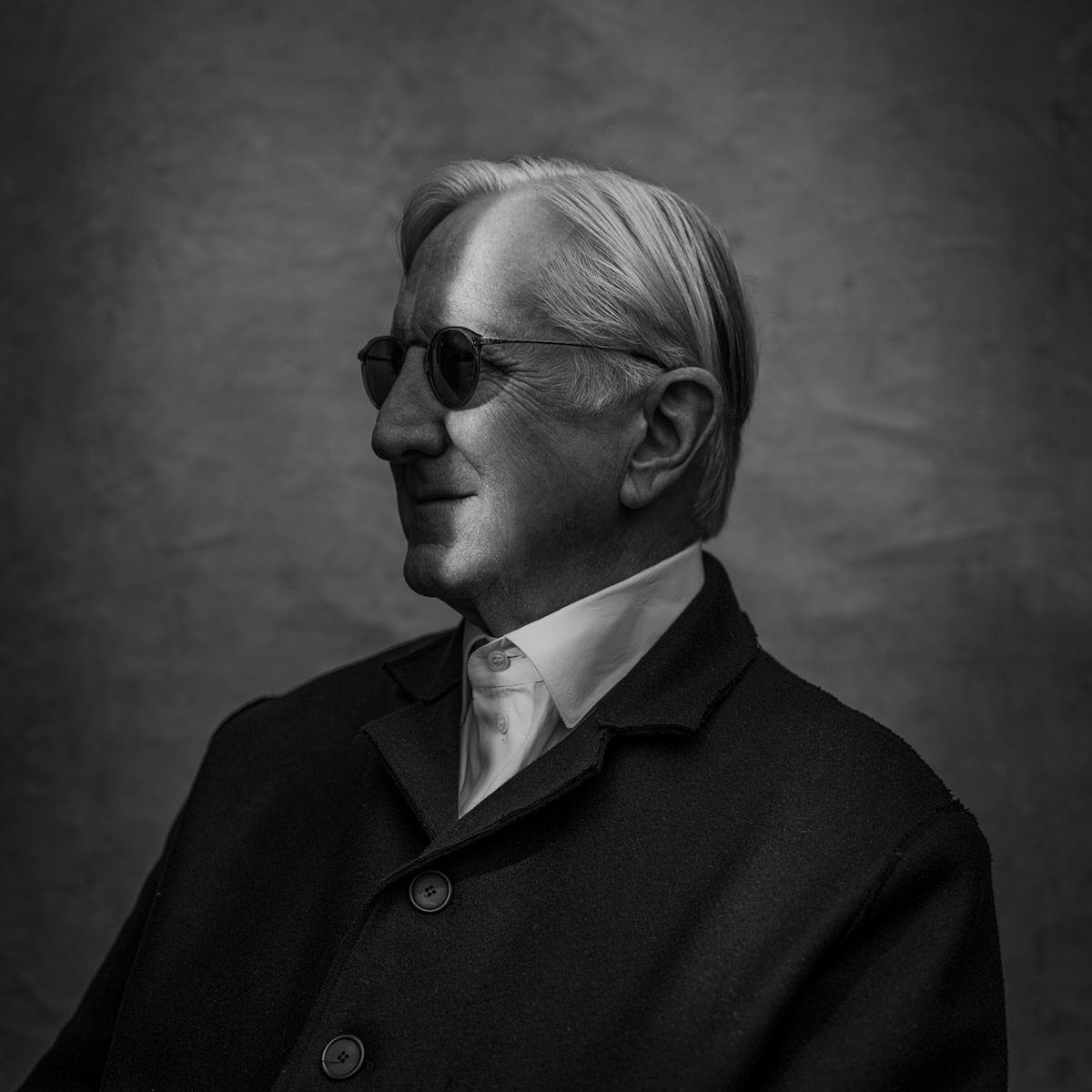 Side portrait of T Bone Burnett in sunglasses with a slice of light vertically across his face