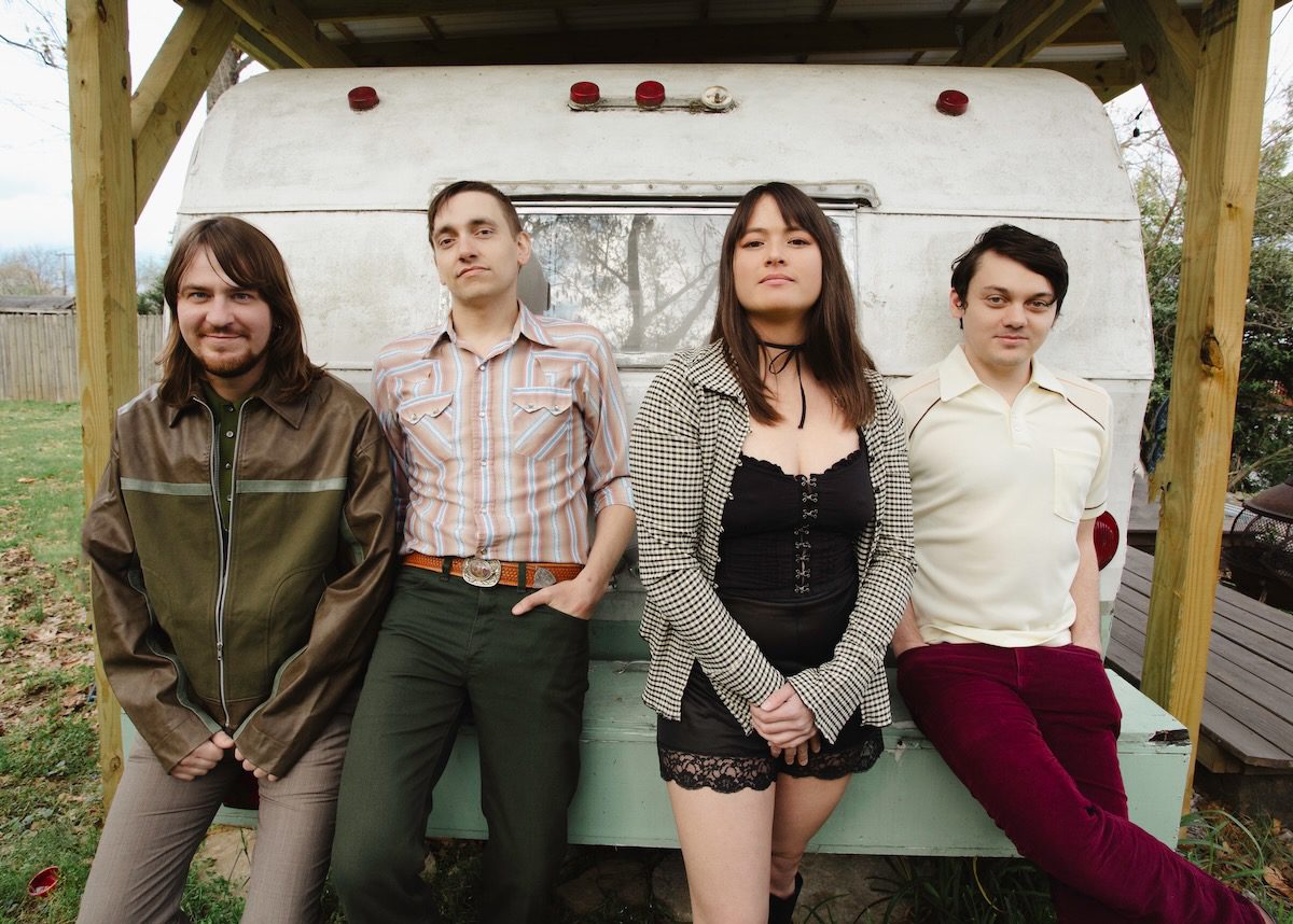 The four members of AJ Lee and Blue Summit in front of the back of a retro camper