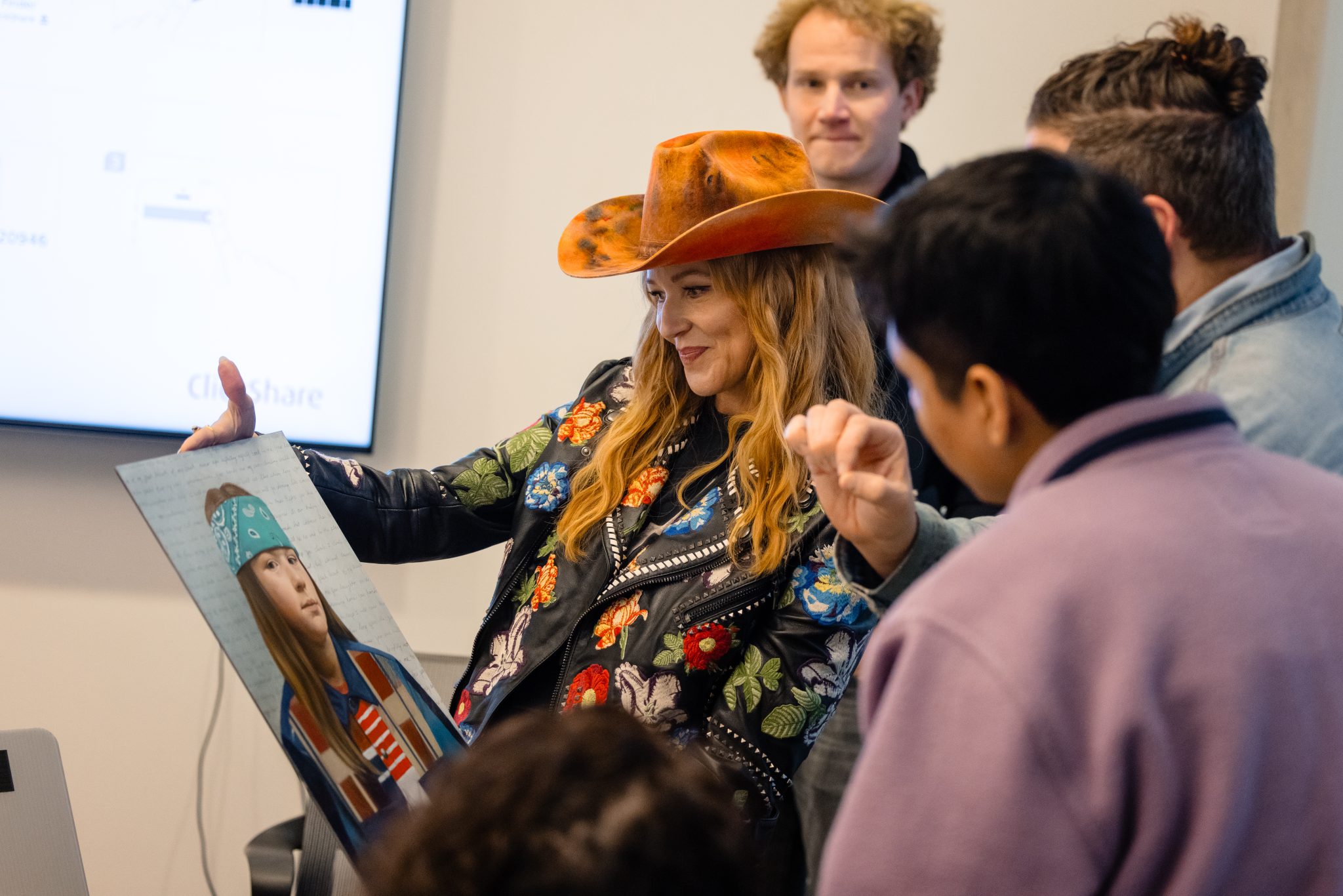 Jewel is surrounded by people as she holds a painting of her son