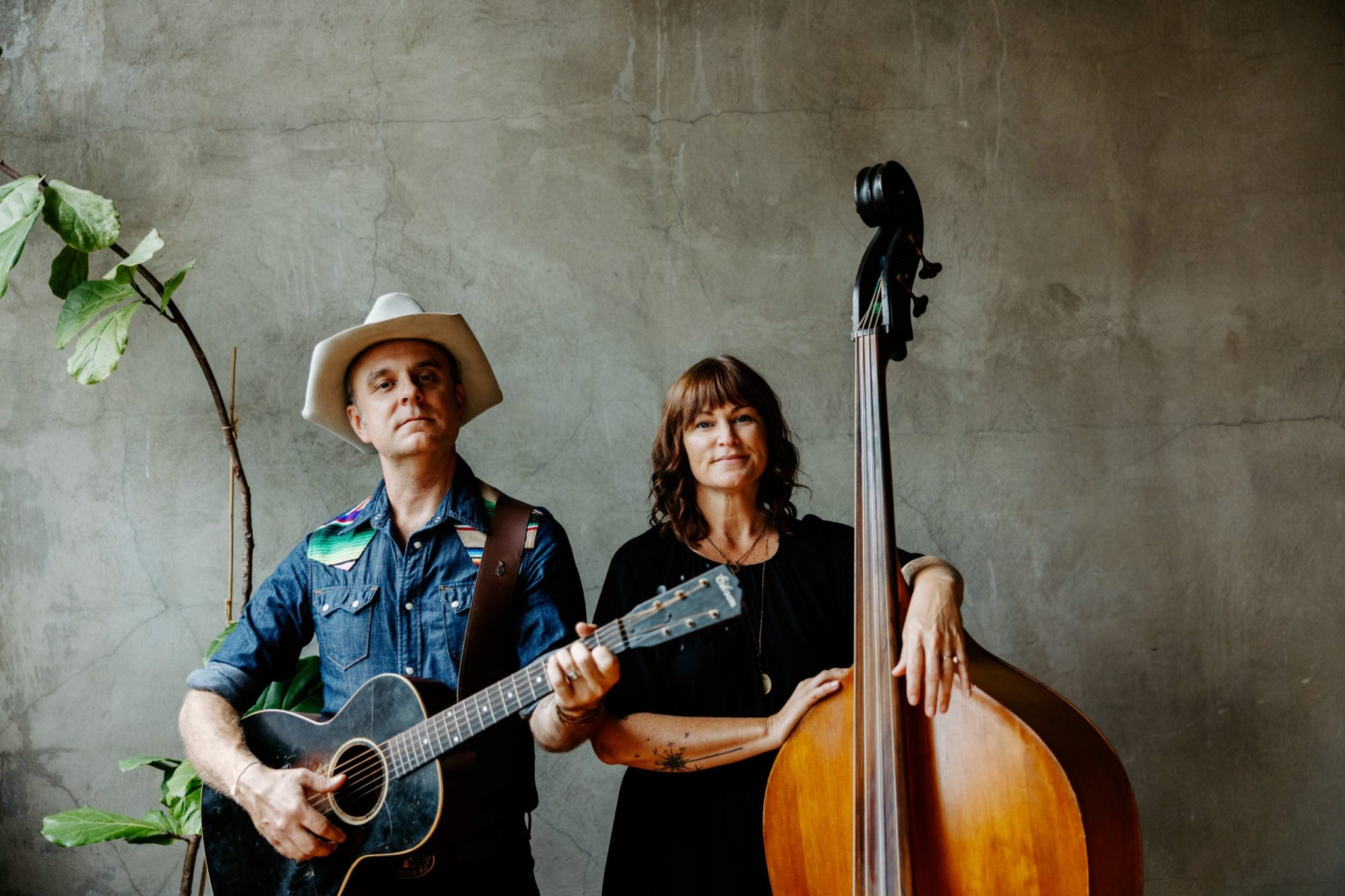 A portrait of Wild Ponies duo holding guitar and upright bass